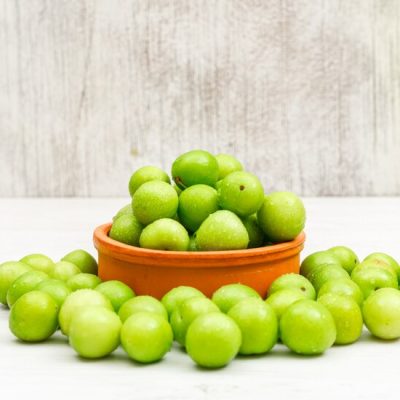 dewy-green-plums-round-clay-bowl-white-grunge-side-view_176474-5285